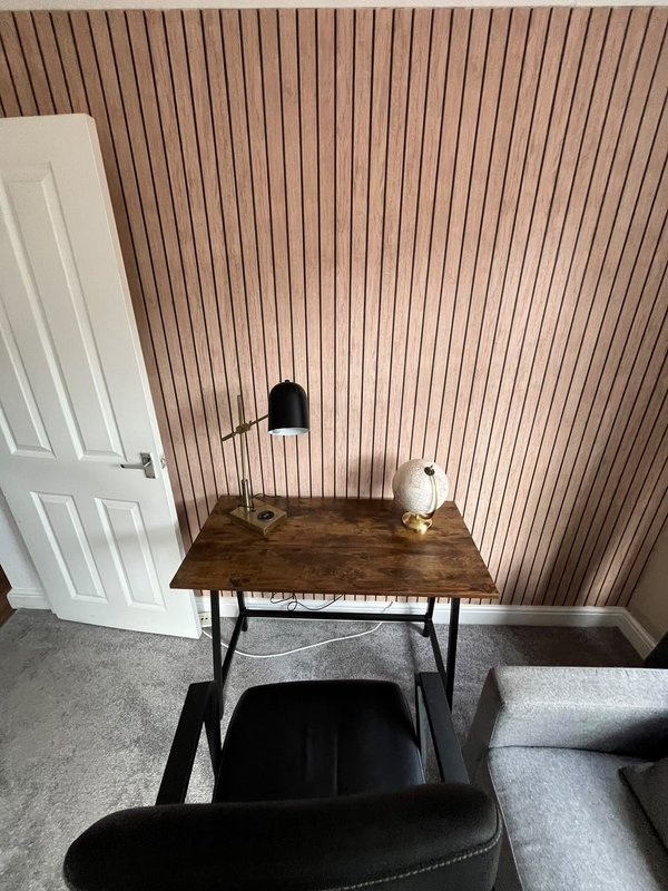 Workspace with wooden desk, black desk lamp, white door and corrugated wall paneling