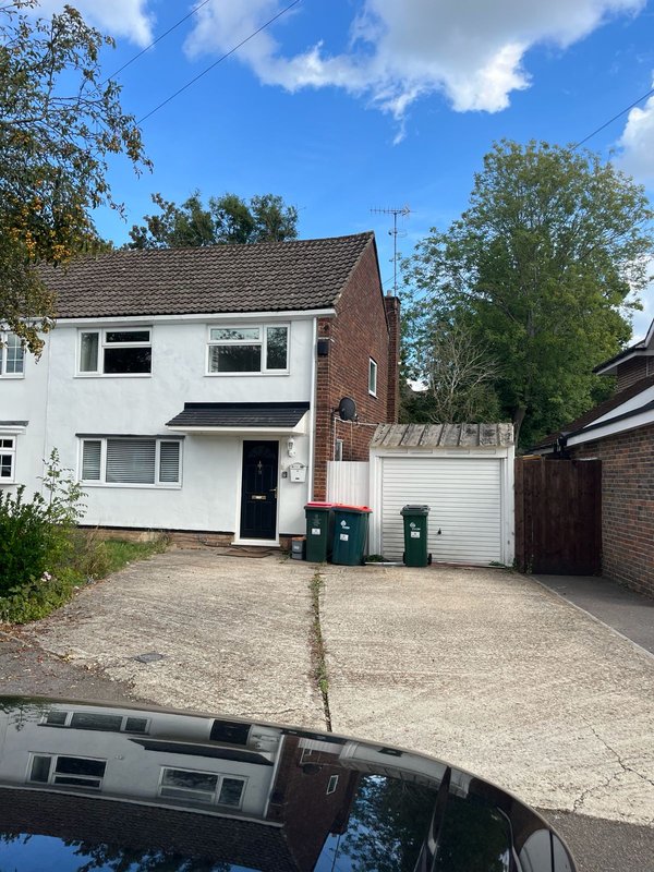 Semi-detached house with brick and white rendered facade, driveway, and garage