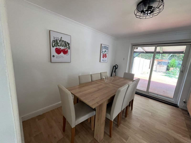 Dining room with wooden table, cream chairs, and glass doors to garden