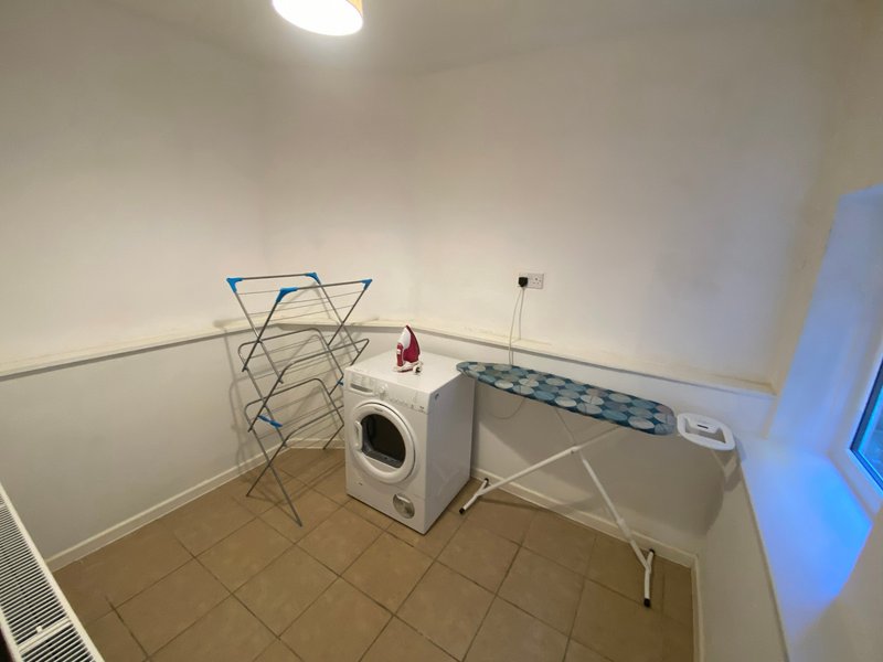Utility room with washing machine, clothes horse, ironing board and ceiling light