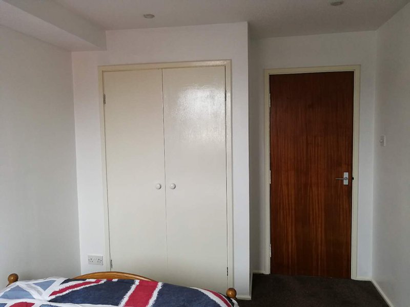 Bedroom corner with cream wardrobe, wooden door, and Union Jack blanket on bed