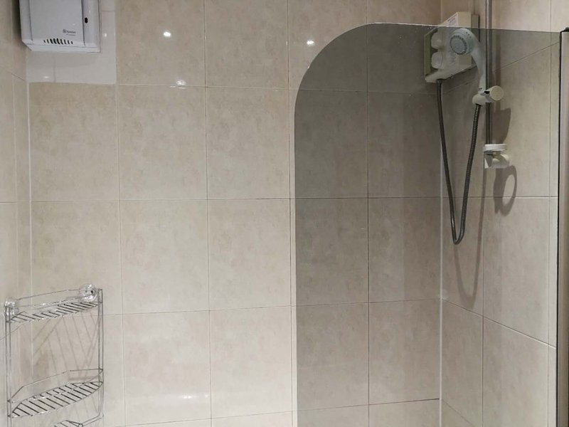 Bathroom with tiled walls, glass shower enclosure, showerhead and chrome fixtures