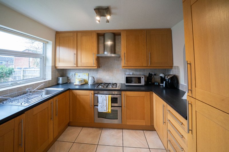Modern kitchen with wooden cabinets, black countertops, stainless steel appliances and window