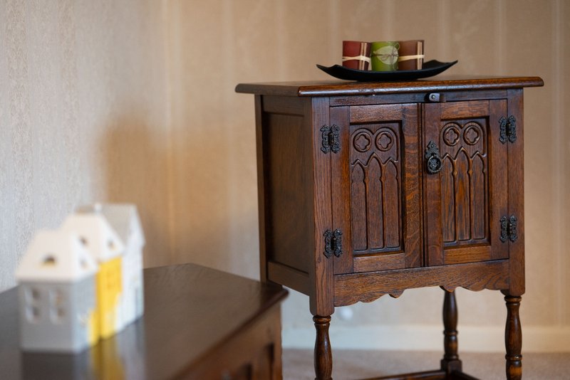 Wooden cabinet with decorative carved doors, ornamental bowl on top, and interior decor items