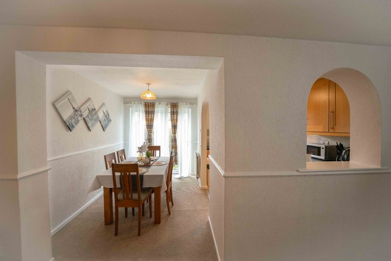 Open-plan interior with dining area, wooden table and chairs, arched alcove with shelving