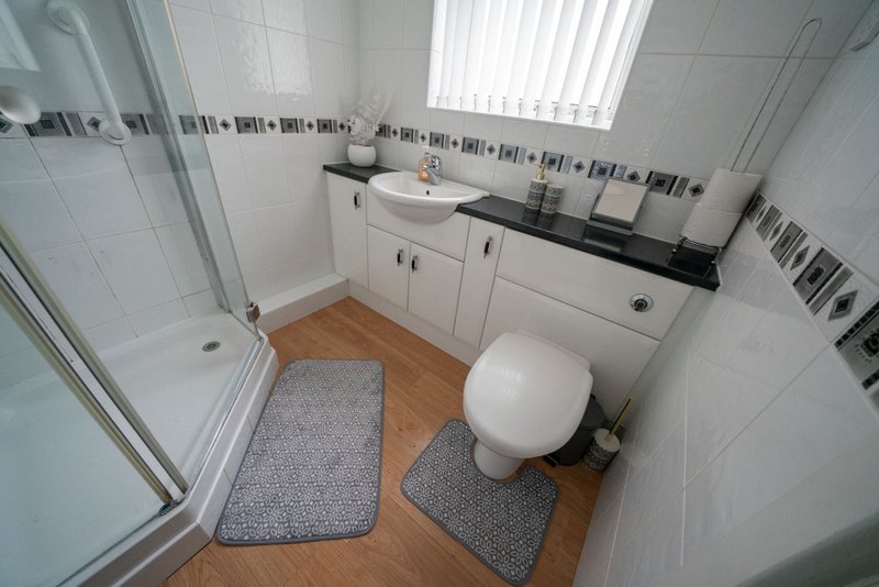 Clean modern bathroom with shower enclosure, white vanity unit, toilet and wooden floor