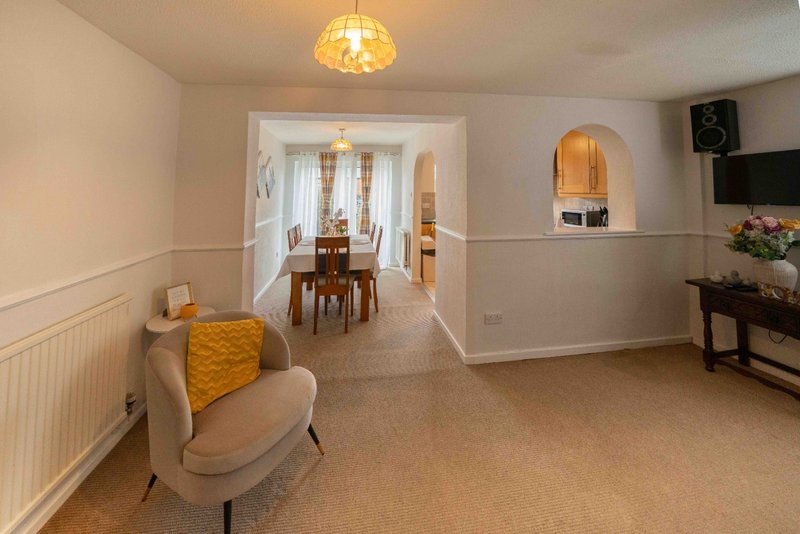Open-plan living area with beige armchair, ceiling light, and view through to dining room