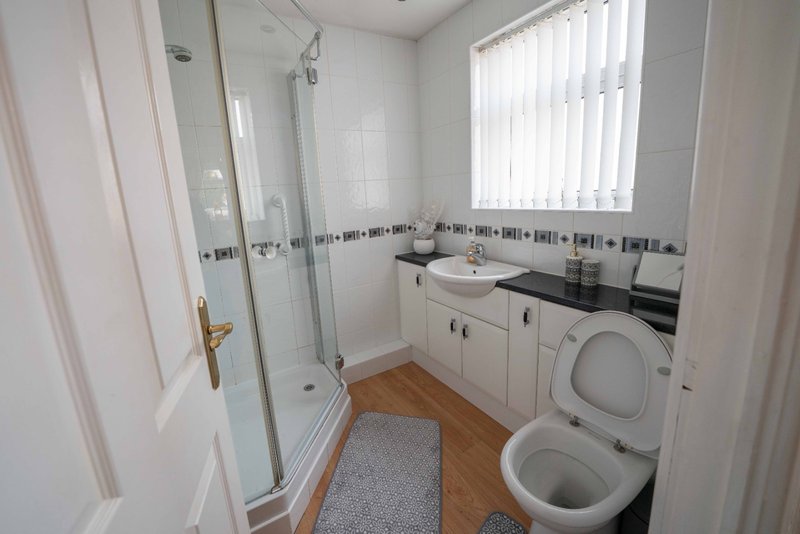 Modern bathroom with shower cubicle, white vanity, toilet, and washing machine