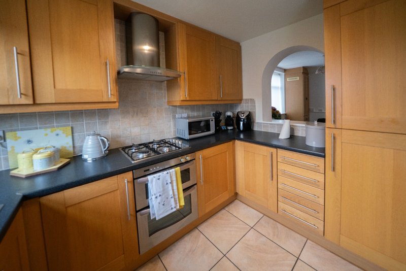 Modern kitchen with wooden cabinets, black countertop, gas hob and stainless steel appliances