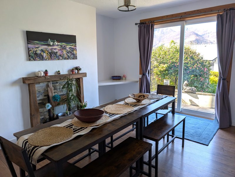Dining room with wooden table, bench seating, fireplace, and glass doors opening to garden views