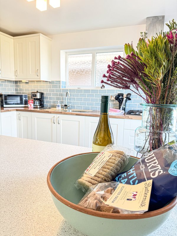 Modern kitchen with white cabinets, blue subway tile backsplash, and island with decorative bowl