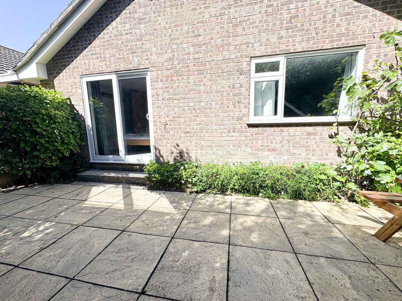 Brick bungalow exterior with patio, French doors, and landscaped garden borders