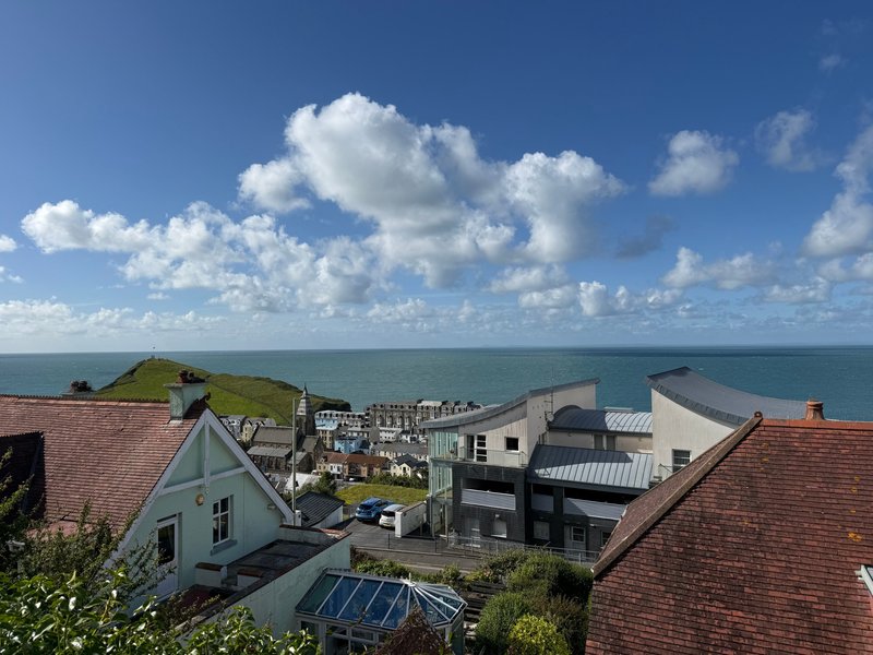 Coastal town view with houses, rooftops, and sea horizon under blue sky