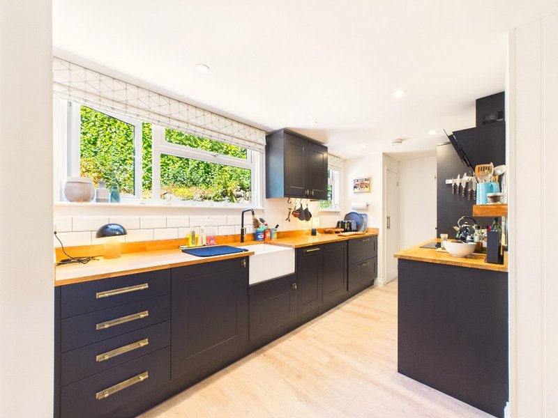 Modern kitchen with dark cabinetry, yellow countertops, white subway tile backsplash and large windows