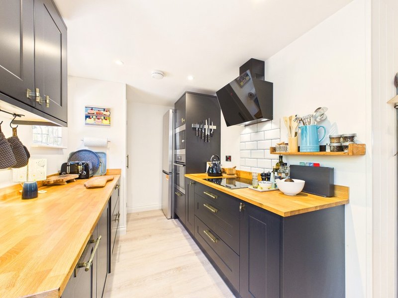 Modern kitchen with dark cabinetry, wooden countertops, white subway tiles, and stainless steel appliances