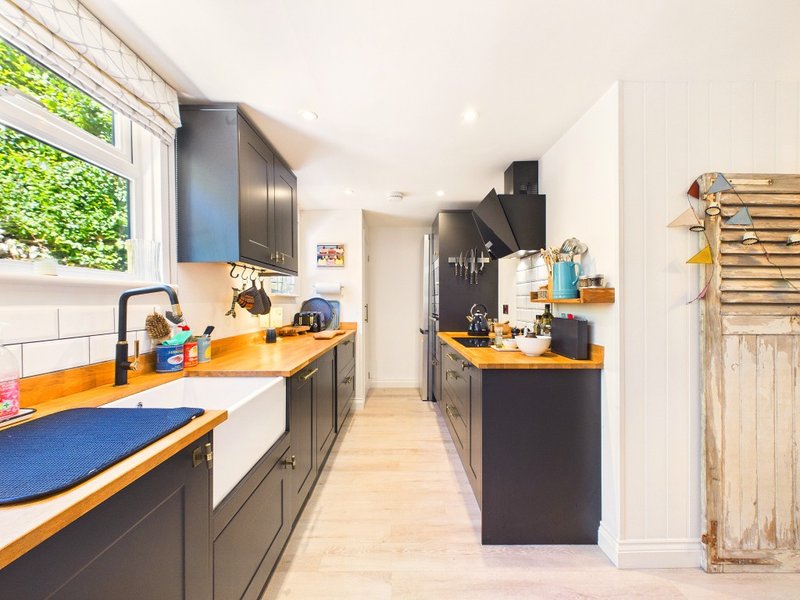 Modern kitchen with black cabinetry, yellow countertops, white subway tiles and wooden flooring