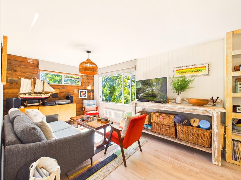 Open-plan living room with grey sofa, wooden furniture, orange pendant light and workspace