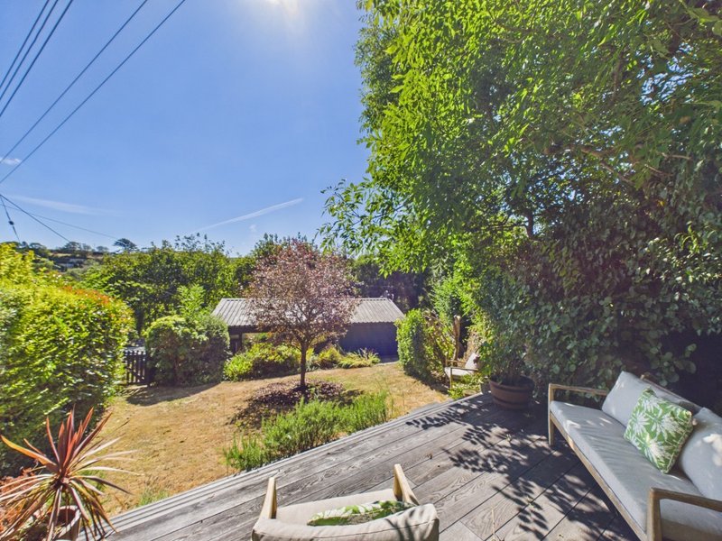 Backyard garden view with decking, loungers, mature trees and residential property