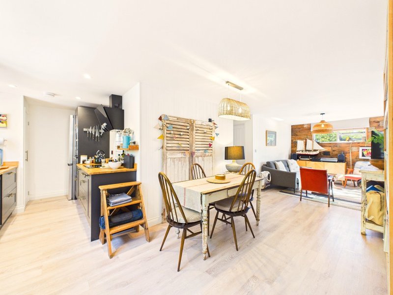 Open-plan living space with kitchen, dining table, and seating area with wooden flooring