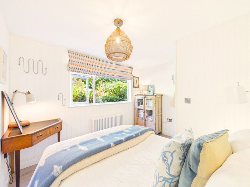 Bright bedroom with single bed, wooden desk, pendant lamp and garden view