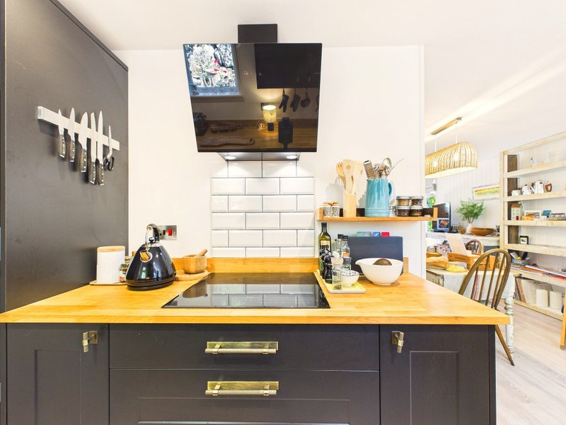 Modern kitchen with yellow countertop, dark cabinetry, subway tile backsplash and open shelving