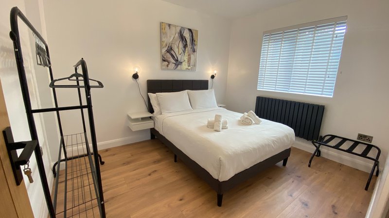 Modern bedroom with double bed, wooden flooring, black metal frame headboard, and wall-mounted lighting