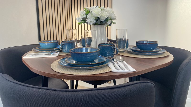 Round dining table set with blue plates, glasses, white flowers and place settings