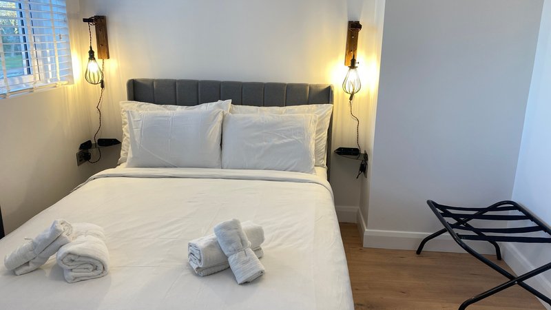 Modern bedroom with white bedding, black upholstered headboard, and warm bedside lighting