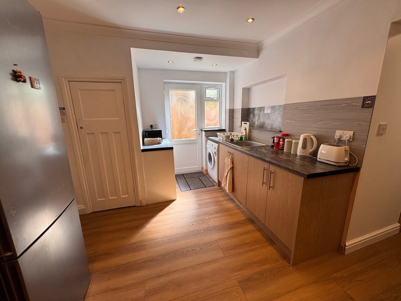 Modern kitchen with wooden cabinets, black countertop, stainless steel appliances and wooden flooring