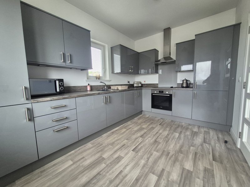 Modern kitchen with gray cabinets, wooden worktops, built-in oven and vinyl flooring