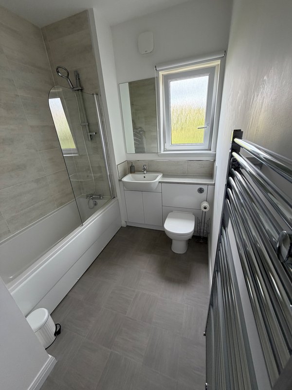 Modern bathroom with shower, toilet, sink, heated towel rail and window