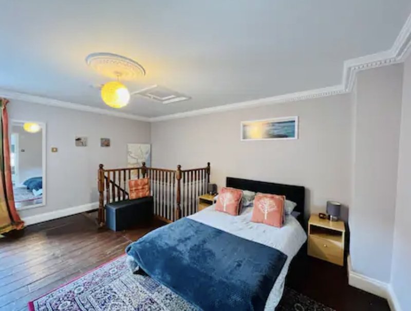 Bright bedroom with double bed, crib, wooden floor, pendant lighting and white walls