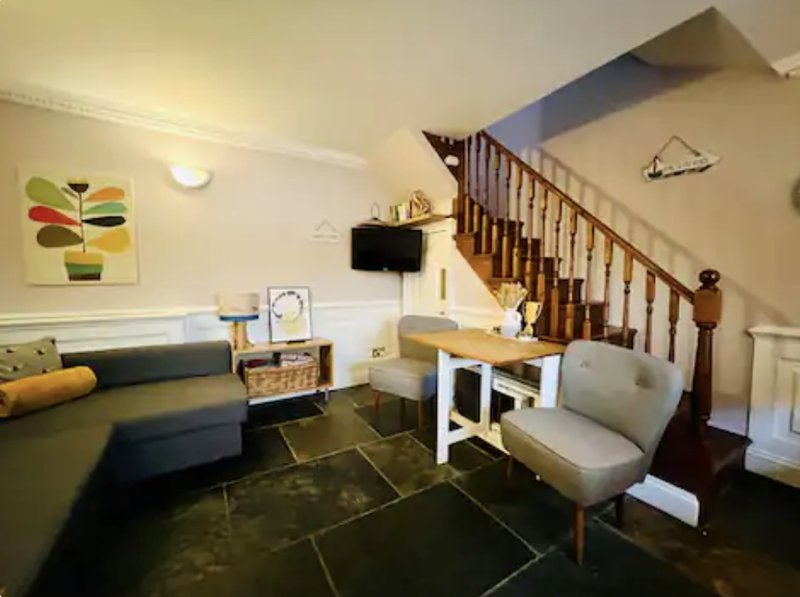 Open-plan living area with sofa, desk, stairs, and modern furnishings