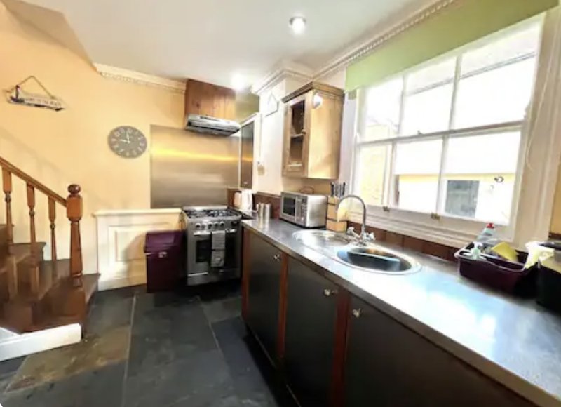 Kitchen with dark cabinetry, stainless steel appliances, black countertops and large window