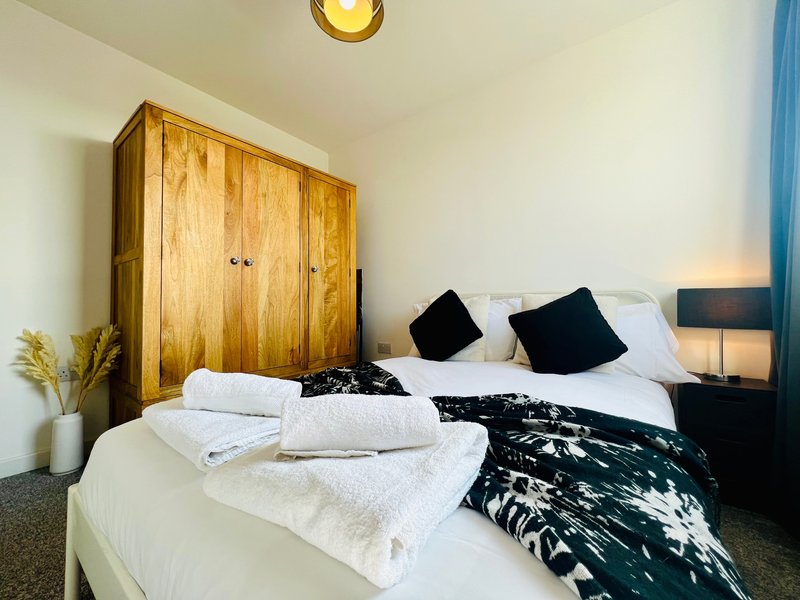 Bedroom with wooden wardrobe, double bed with white pillows and folded towels