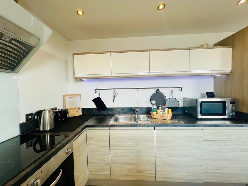 Modern kitchen with cream cabinets, black countertop, stainless steel appliances and pendant lighting