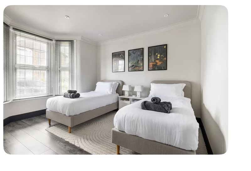 Bright twin bedroom with two single beds, white bedding, large windows and wall art