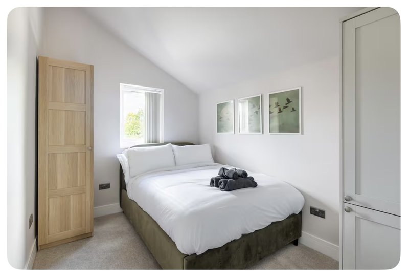Bright bedroom with double bed, wooden door, window, and framed wall art