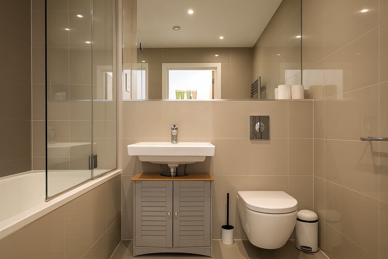Modern bathroom with bathtub, sink vanity, toilet, and recessed lighting