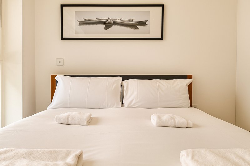 Bedroom with double bed, white bedding, wooden headboard and framed wall art