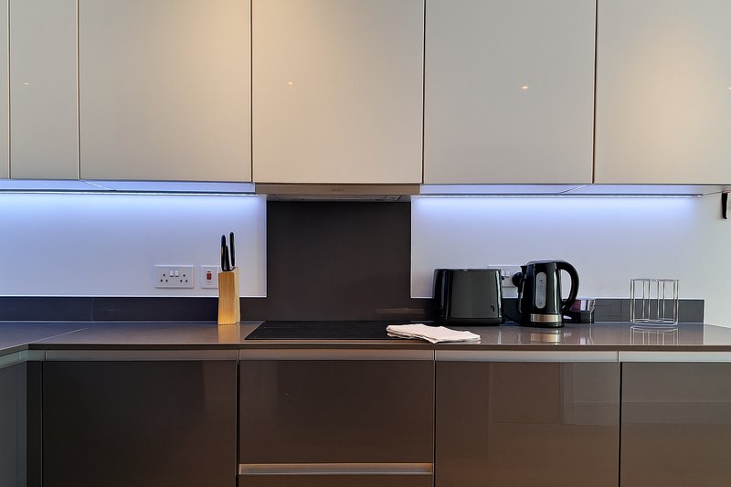 Modern kitchen with dark lower cabinets, light upper cabinets, black backsplash and countertop appliances