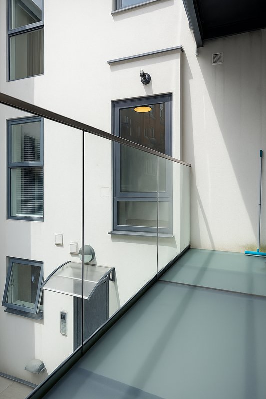 Modern building exterior with glass door, railing, and multiple windows on white wall