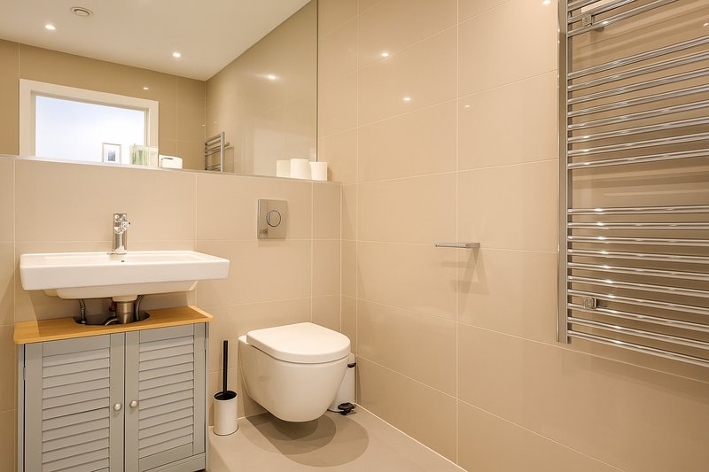 Modern bathroom with wall-mounted sink, toilet, heated towel rail and shower enclosure