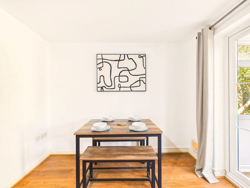 Dining area with wooden table, bench seating, abstract wall art and glass door