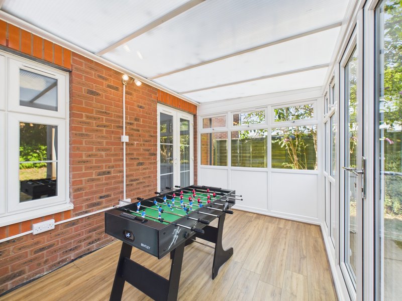 Conservatory with foosball table, brick walls, wooden flooring and glass doors