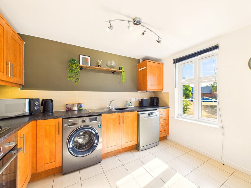 Modern kitchen with orange cabinets, washing machine, dishwasher and window with garden view