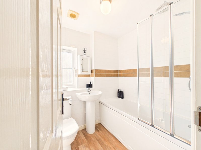 Clean bathroom with pedestal sink, toilet, shower enclosure and wooden floor