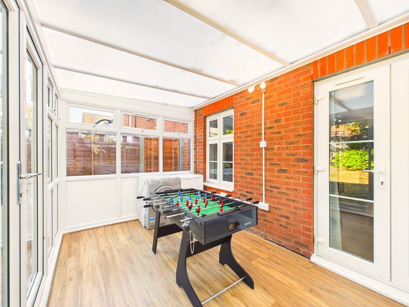 Conservatory with foosball table, wooden flooring, brick walls and glass doors