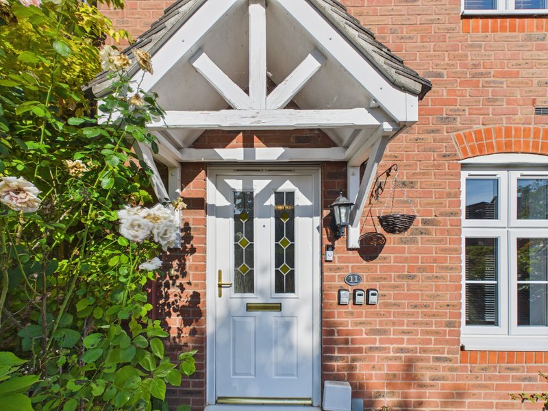 Red brick house exterior with white-framed entrance porch, climbing ivy, and white-trimmed windows
