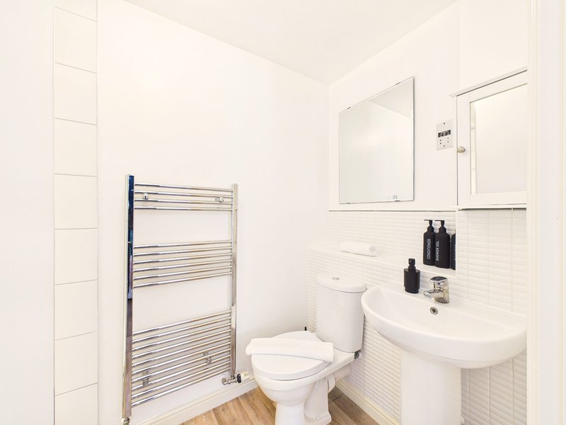 Modern bathroom with white tiles, heated towel rail, toilet, sink and mirror